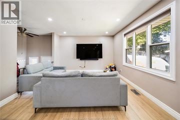 Windsor apartment for rent - A living room with a grey couch and a flat screen TV mounted on the wall.