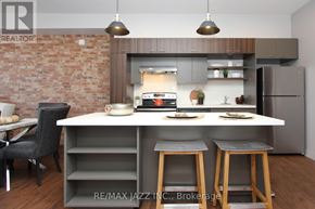 Oshawa (O'neill) multi-family for rent - A modern kitchen with a brick wall and a dining area.