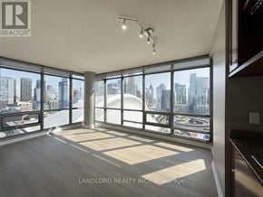 Toronto (Waterfront Communities) condo for rent - A spacious room with large windows overlooking a cityscape.