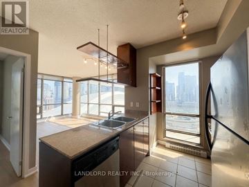 Toronto (Waterfront Communities) condo for rent - A kitchen with a large island and a view of the city outside the window.