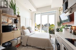 Toronto (Humewood-Cedarvale) condo for rent - A well-lit bedroom with a large bed and a kitchen area with a stove top oven.