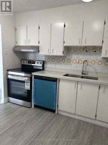 Toronto (Tam O'shanter-Sullivan) condo for rent - A kitchen with white cabinets and a blue dishwasher.