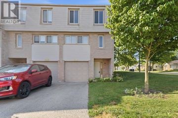 London North (North I) townhouse for rent - A red car is parked in front of a two-story building with a garage.