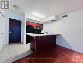 Ottawa condo for rent - A kitchen area with a black fridge, black microwave, and a white counter.