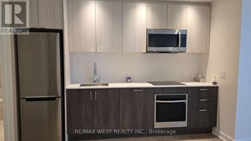 Toronto (South Parkdale) condo for rent - A kitchen with a refrigerator, microwave, and oven.