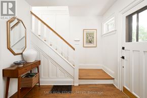 Toronto (Weston) apartment for rent - A hallway with a wooden staircase and a mirror on the side table.