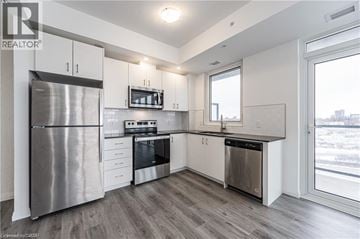 Kitchener condo for rent - A modern kitchen with stainless steel appliances and white cabinets.