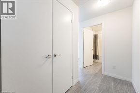 Kitchener condo for rent - A white door with a silver handle is in a room with a tiled floor.