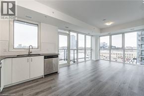 Kitchener condo for rent - A spacious kitchen with white cabinets and a large window overlooking the city.
