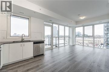 Kitchener condo for rent - A spacious kitchen with white cabinets and a large window overlooking the city.