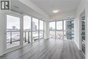 Kitchener condo for rent - A spacious room with a view of the city through large windows.
