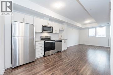 Kitchener condo for rent - A modern kitchen with a stainless steel refrigerator and wooden flooring.