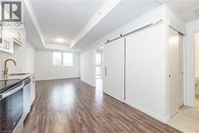 Kitchener condo for rent - A spacious kitchen with white cabinets and a wooden floor.