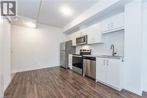 Kitchener condo for rent - A kitchen with white cabinets and stainless steel appliances.