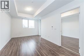 Kitchener condo for rent - A spacious room with wooden flooring and white walls.