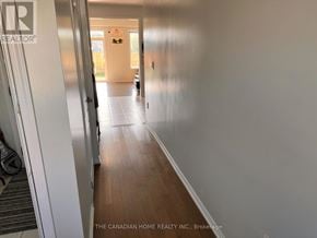 Thorold (Hurricane/Merrittville) apartment for rent - A hallway with a door on the left and a person standing in the distance.