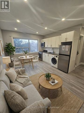 Toronto (Bedford Park-Nortown) multi-family for rent - A well-lit, modern kitchen and living room with a grey sofa and wooden coffee table.