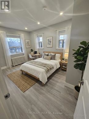 Toronto (Bedford Park-Nortown) multi-family for rent - A bedroom with a large bed and a window with white curtains.