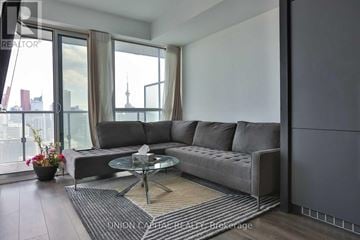 Toronto (Bay Street Corridor) condo for rent - A modern living room with a grey sofa and a glass table.