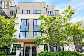 Pickering (Town Centre) townhouse for rent - A modern building with a beige facade and large windows is surrounded by green trees.