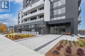 Guelph (St. Patrick's Ward) condo for rent - A modern building with a grey and white facade and a landscaped courtyard in front.