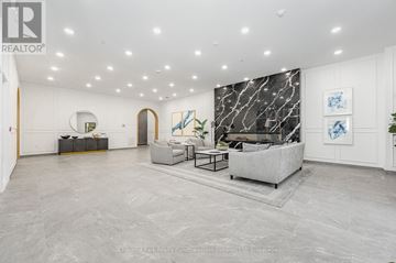 Guelph (St. Patrick's Ward) condo for rent - A spacious living room with a grey sofa and a marble wall.