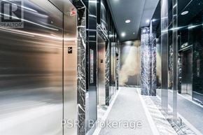 Toronto (Waterfront Communities) condo for rent - A hallway with a marble floor and walls, and a glass elevator with the letters "G" on it.