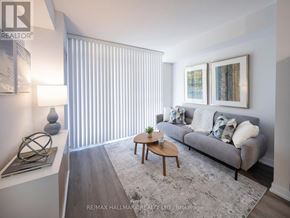 Toronto (Moss Park) condo for rent - A living room with a grey couch, a coffee table, and a large window with blinds.