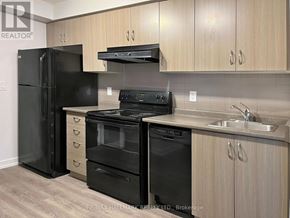 Toronto (Moss Park) condo for rent - A kitchen with black appliances and wooden cabinets.