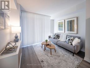 Toronto (Moss Park) condo for rent - A living room with a grey couch, a coffee table, and a large window with blinds.