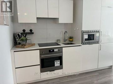 Toronto (Kensington-Chinatown) condo for rent - A modern kitchen with white cabinets and a black oven.