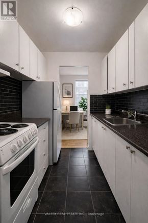 Toronto (Wexford-Maryvale) condo for rent - A modern kitchen with white cabinets and black countertops.
