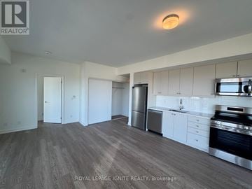 Clarington (Bowmanville) condo for rent - A kitchen with white cabinets and a stainless steel refrigerator.