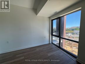 Clarington (Bowmanville) condo for rent - A room with a large window and wooden flooring is for sale.
