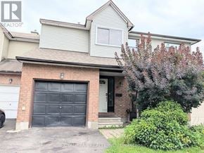 Ottawa townhouse for rent - A house with a garage door and a tree in front.