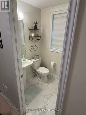 Thorold (Rolling Meadows) townhouse for rent - A bathroom with a toilet, sink, and mirror.