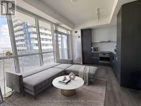 Vaughan (Vaughan Corporate Centre) condo for rent - A modern living room with a grey sofa and a round coffee table.