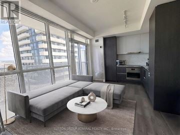 Vaughan (Vaughan Corporate Centre) condo for rent - A modern living room with a grey sofa and a round coffee table.