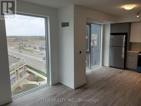 Burlington (Alton) condo for rent - A room with a view of a parking lot and buildings outside.
