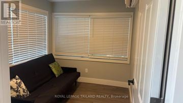 Central Elgin (Port Stanley) fourplex for rent - A living room with a couch and a window with blinds.