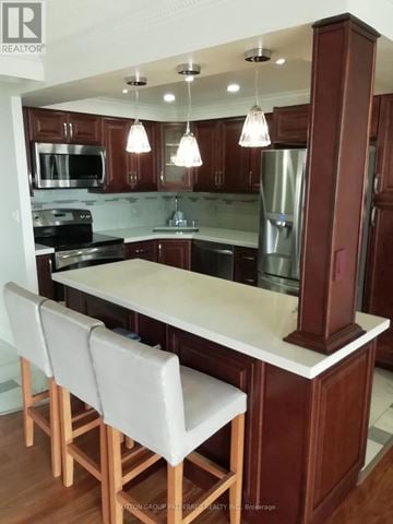 London East (East K) condo for rent - A kitchen with brown cabinets and a white island.