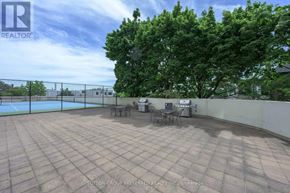 London East (East K) condo for rent - A patio with a table and chairs is surrounded by a fence and trees.