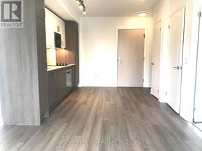 Toronto (Church-Yonge Corridor) condo for rent - A room with wooden flooring and a kitchen area with white cabinets.