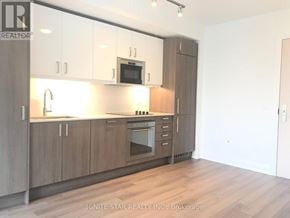 Toronto (Church-Yonge Corridor) condo for rent - A kitchen with wooden cabinets and a microwave above the oven.