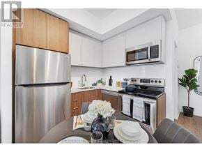 Toronto (Oakridge) townhouse for rent - A modern kitchen with a stainless steel refrigerator and a dining table set for two.