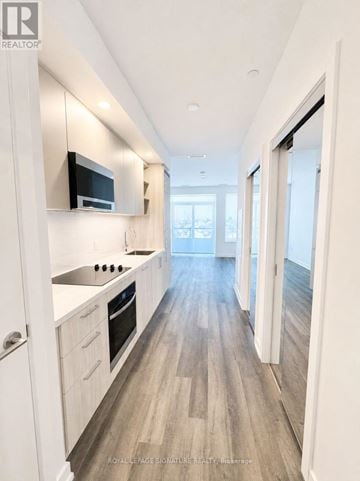Vaughan (Vaughan Corporate Centre) condo for rent - A modern kitchen with white cabinets and a wooden floor.