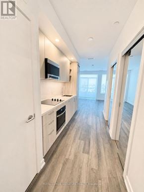 Vaughan (Vaughan Corporate Centre) condo for rent - A modern kitchen with white cabinets and a flat screen TV mounted above the stove.