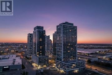 Vaughan (Vellore Village) condo for rent - A cityscape at dusk with a prominent building in the foreground and a logo in the top left corner.