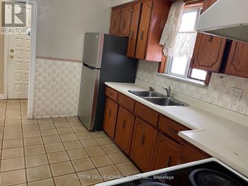 Toronto (Briar Hill-Belgravia) apartment for rent - A kitchen with a black fridge, brown cabinets and a tiled floor.