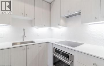 Kitchener condo for rent - A modern kitchen with white cabinets and a stainless steel sink.